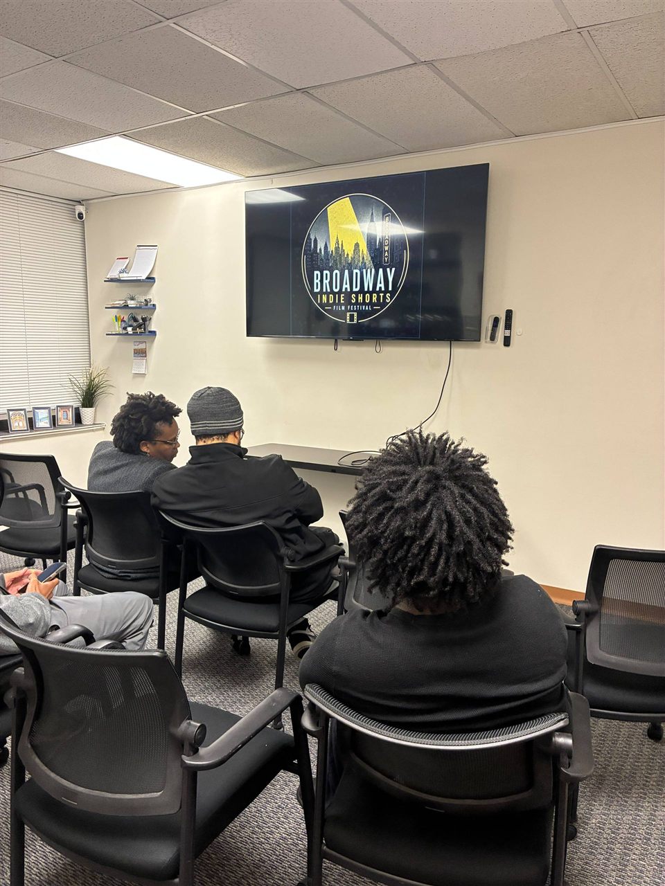 Guests seated in the screening room as the Broadway Indie Shorts logo plays on the screen.