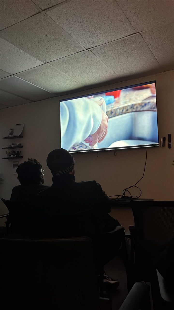 Audience members watching a screening in the darkened room.